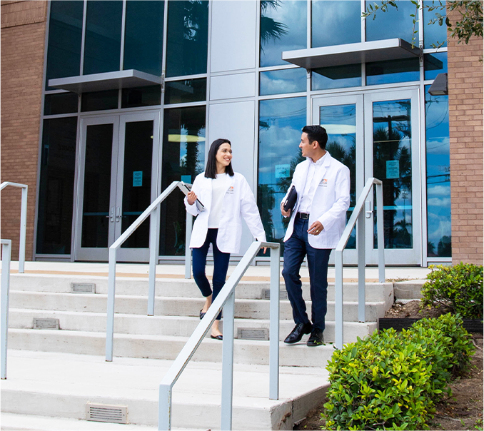 physician assistant students wearing lab coats while walking on campus